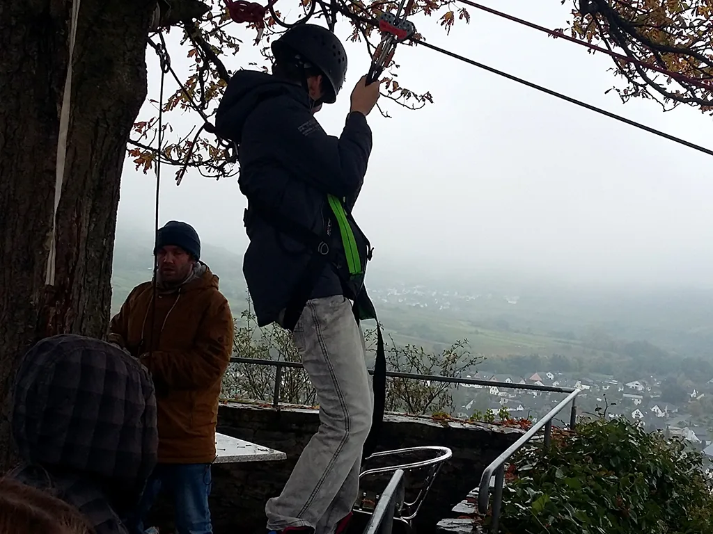 Person hängt sich in die Seilrutsche über dem Tal ein.